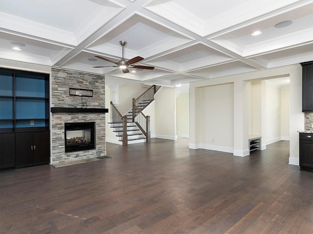 unfurnished living room featuring dark hardwood / wood-style floors, a stone fireplace, and ceiling fan