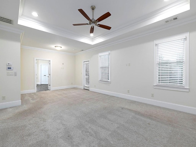 carpeted empty room with ceiling fan, a raised ceiling, and crown molding