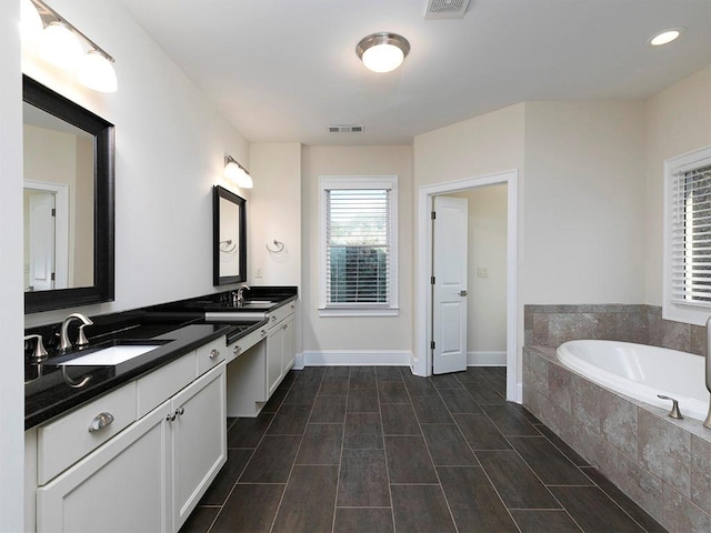 bathroom featuring tiled bath and vanity