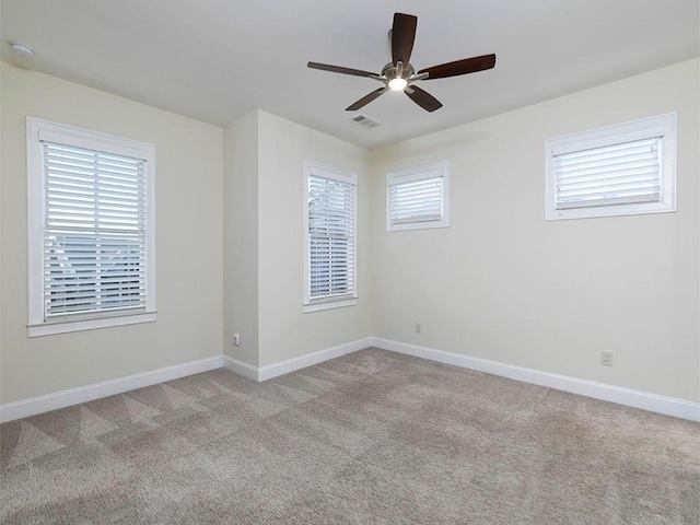 carpeted spare room featuring plenty of natural light and ceiling fan