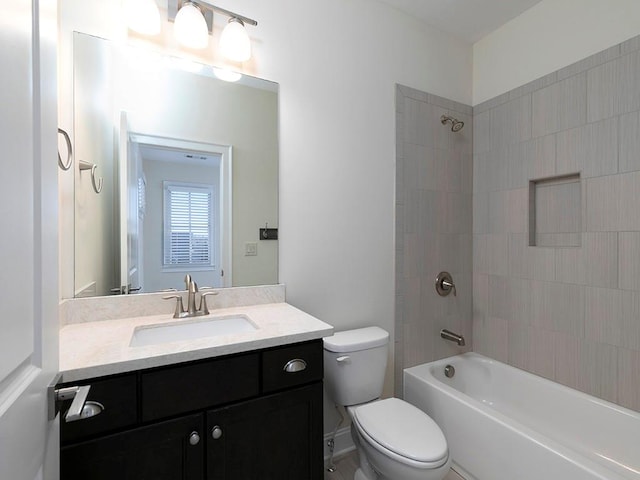 full bathroom featuring tiled shower / bath combo, toilet, and vanity