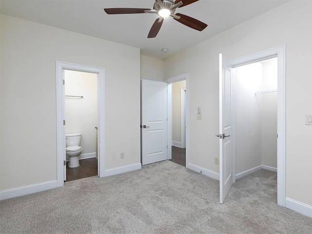 unfurnished bedroom featuring a walk in closet, ceiling fan, ensuite bathroom, and light colored carpet