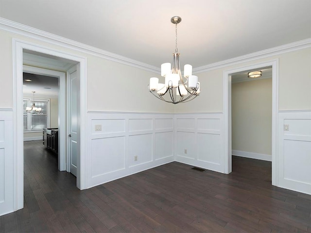 unfurnished dining area with dark hardwood / wood-style floors, crown molding, and an inviting chandelier