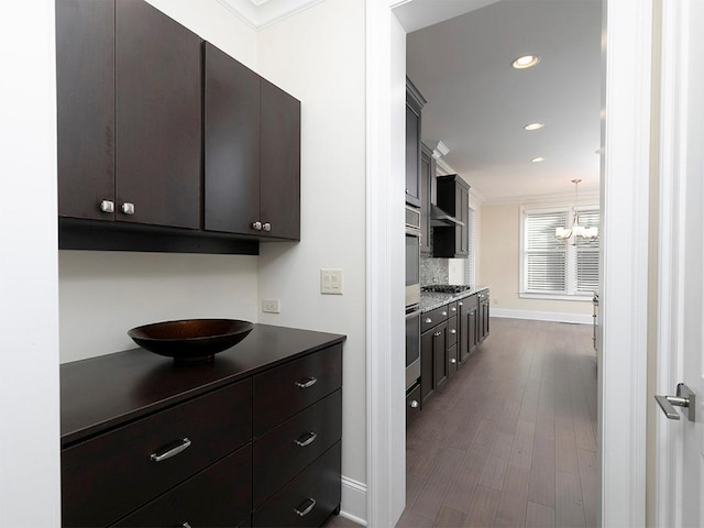 kitchen featuring appliances with stainless steel finishes, dark brown cabinetry, crown molding, a chandelier, and hardwood / wood-style floors