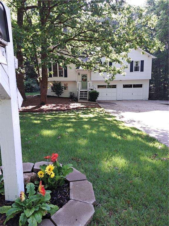 view of green lawn with driveway and a garage