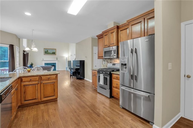2810 Olde Town Park Dr, Norcross, GA 30071 - kitchen featuring light stone counters, brown cabinets, stainless steel appliances, light wood-type flooring, and a fireplace