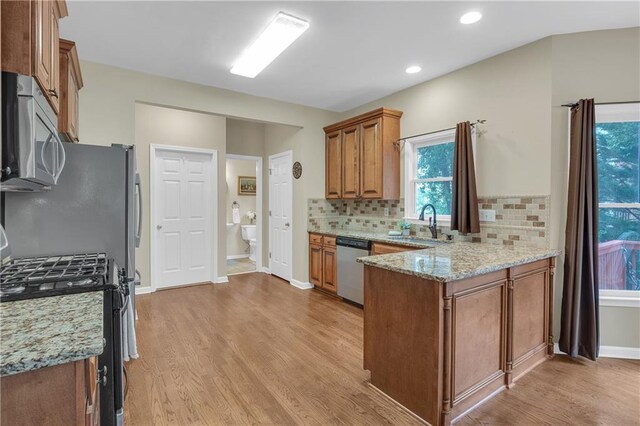 2810 Olde Town Park Dr, Norcross, GA 30071 - kitchen featuring light wood finished floors, a sink, stainless steel appliances, brown cabinetry, and a peninsula