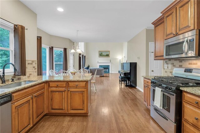 2810 Olde Town Park Dr, Norcross, GA 30071 - kitchen with light wood-style floors, appliances with stainless steel finishes, brown cabinets, a fireplace, and a sink