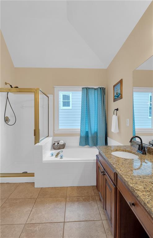 2810 Olde Town Park Dr, Norcross, GA 30071 - full bathroom with vanity, a stall shower, vaulted ceiling, a garden tub, and tile patterned flooring