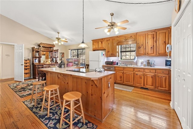 kitchen with light wood-style floors, vaulted ceiling, black electric cooktop, and freestanding refrigerator