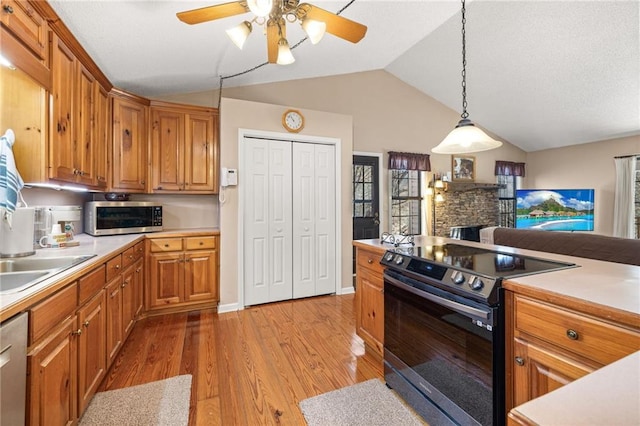 kitchen with lofted ceiling, light wood-style flooring, stainless steel appliances, and light countertops