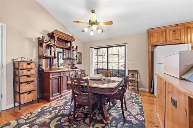 dining area featuring light wood-style flooring, baseboards, vaulted ceiling, and a ceiling fan