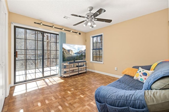 sitting room featuring ceiling fan, a textured ceiling, and baseboards