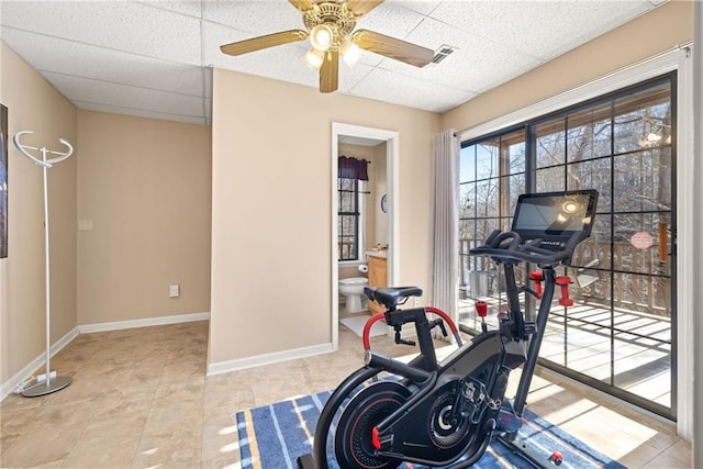 workout area with a ceiling fan, visible vents, baseboards, and a drop ceiling