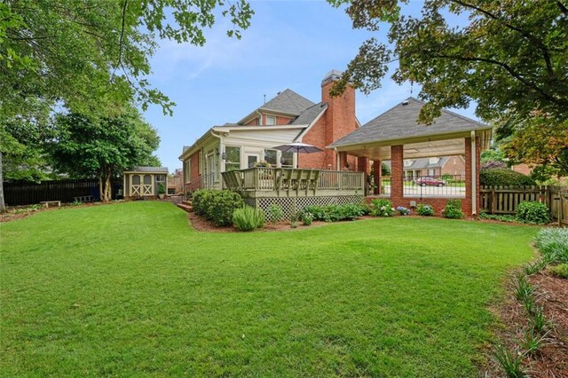 rear view of property with a deck, a lawn, and a shed