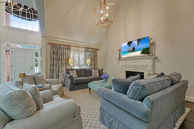 carpeted living room with a fireplace, a towering ceiling, and an inviting chandelier