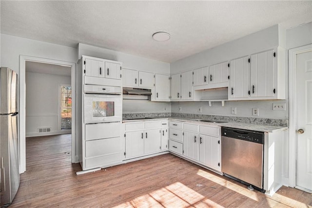 kitchen featuring visible vents, appliances with stainless steel finishes, light wood-style floors, white cabinetry, and under cabinet range hood