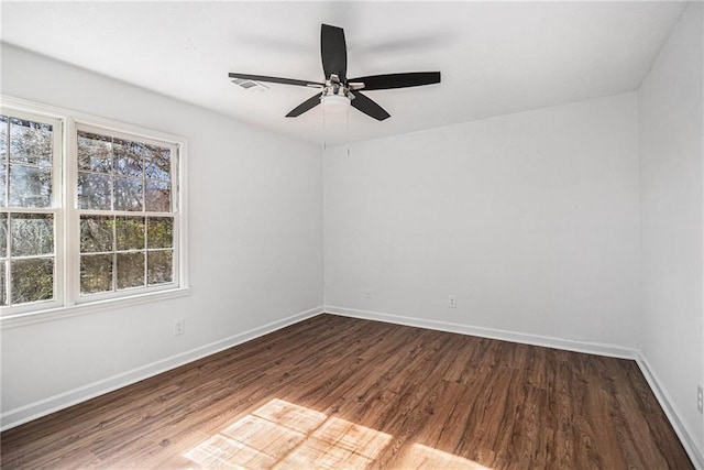 unfurnished room with a ceiling fan, visible vents, baseboards, and wood finished floors