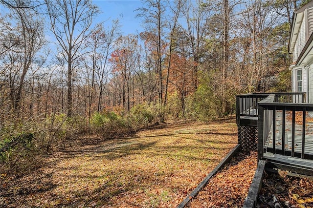 view of yard featuring a deck and a view of trees