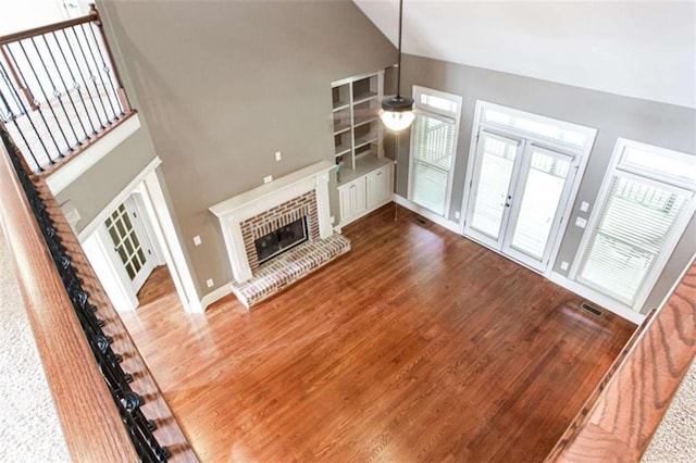 240 Chandler Walk, Loganville, GA 30052 - unfurnished living room featuring wood finished floors, french doors, a brick fireplace, high vaulted ceiling, and stairs