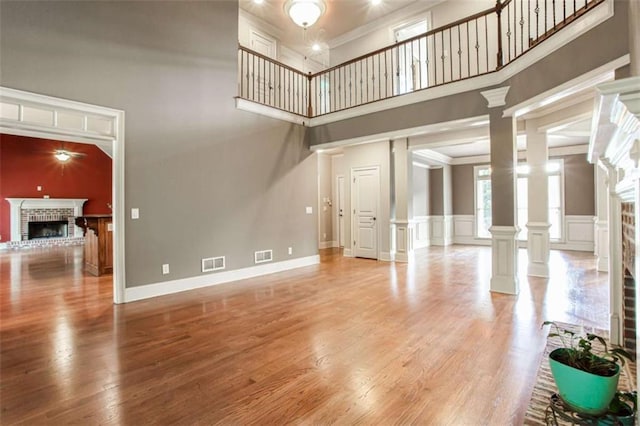 240 Chandler Walk, Loganville, GA 30052 - unfurnished living room featuring a brick fireplace, ornamental molding, a high ceiling, light wood-style floors, and ceiling fan