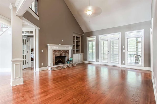 240 Chandler Walk, Loganville, GA 30052 - unfurnished living room with built in shelves, high vaulted ceiling, healthy amount of natural light, and wood finished floors