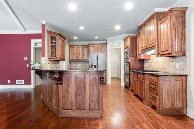 240 Chandler Walk, Loganville, GA 30052 - kitchen with brown cabinets, a kitchen bar, glass insert cabinets, decorative backsplash, and dark wood-style flooring