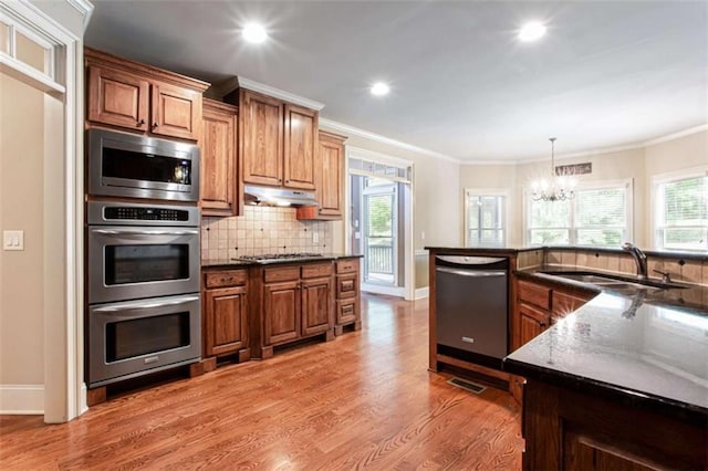 240 Chandler Walk, Loganville, GA 30052 - kitchen with stainless steel appliances, a chandelier, light wood finished floors, decorative backsplash, and plenty of natural light