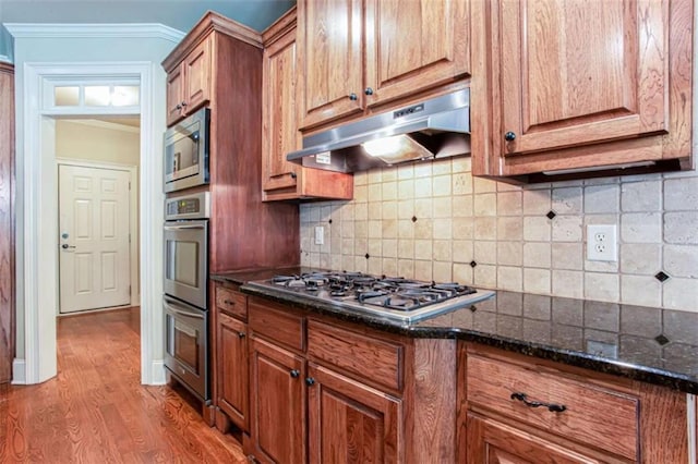 240 Chandler Walk, Loganville, GA 30052 - kitchen with under cabinet range hood, stainless steel appliances, wood finished floors, dark stone counters, and crown molding