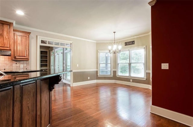 240 Chandler Walk, Loganville, GA 30052 - kitchen featuring dark countertops, a chandelier, dark wood-type flooring, backsplash, and brown cabinetry
