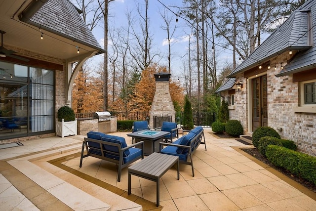 view of patio / terrace with exterior kitchen, an outdoor fire pit, fence, and area for grilling