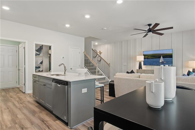 kitchen with ceiling fan, dishwasher, sink, gray cabinets, and a center island with sink