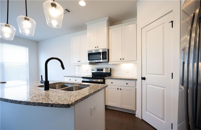 kitchen with stone counters, appliances with stainless steel finishes, white cabinets, and decorative light fixtures