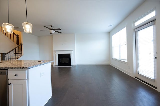 kitchen featuring white cabinetry, light stone counters, dark hardwood / wood-style floors, pendant lighting, and ceiling fan