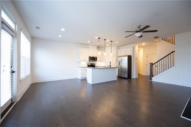 kitchen featuring hanging light fixtures, a kitchen island, white cabinets, and appliances with stainless steel finishes