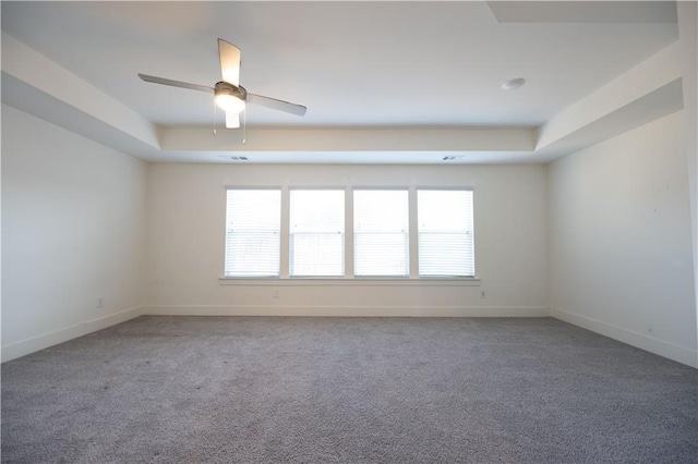 carpeted empty room featuring plenty of natural light, a raised ceiling, and ceiling fan