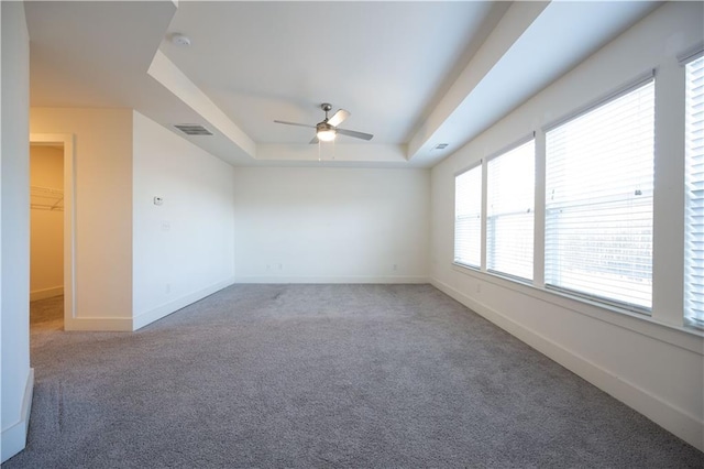 carpeted spare room featuring a raised ceiling and ceiling fan