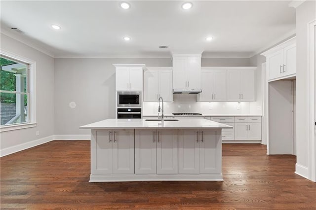 kitchen with white cabinets, sink, dark hardwood / wood-style floors, a kitchen island with sink, and stainless steel microwave