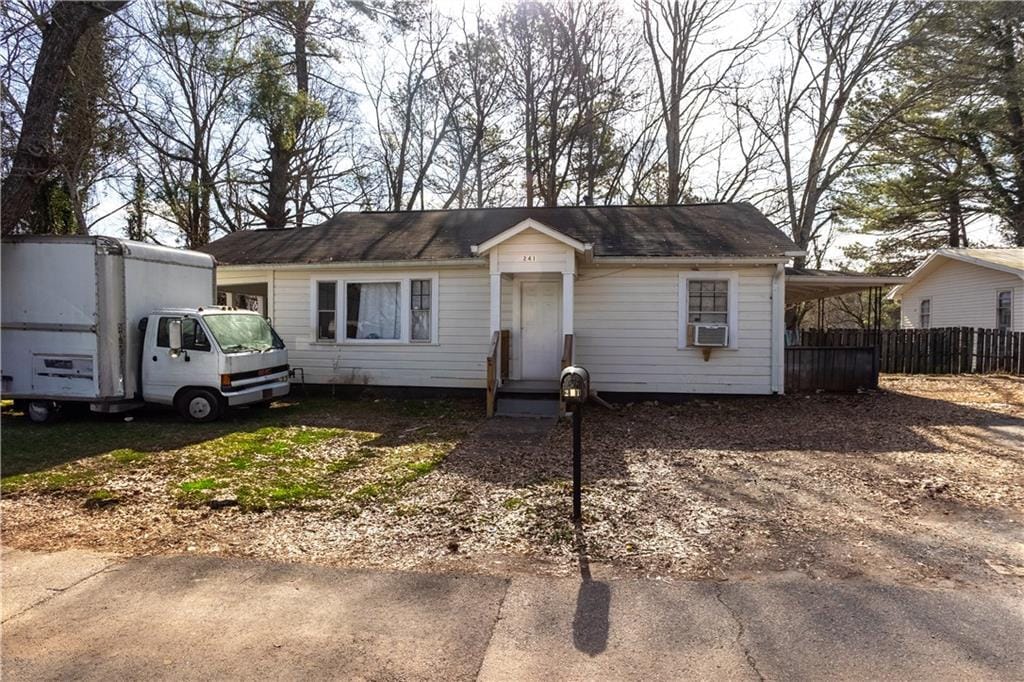 view of front of house with cooling unit, an attached carport, driveway, and fence