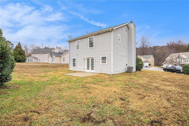 back of house with central AC unit, a lawn, a chimney, french doors, and a patio area