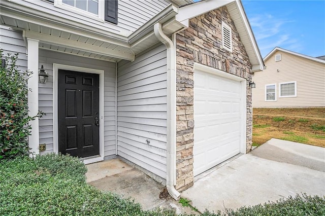 doorway to property featuring an attached garage and stone siding