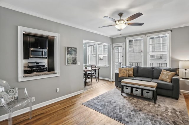 living room featuring hardwood / wood-style flooring, ceiling fan, and crown molding