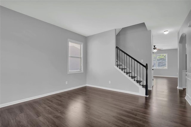 581 Collingsworth Ln, Lawrenceville, GA 30043 - unfurnished living room with a ceiling fan, stairs, dark wood finished floors, baseboards, and arched walkways
