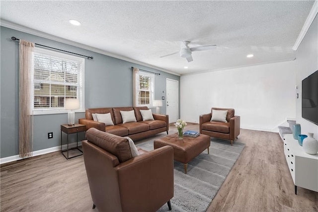 living area with baseboards, a ceiling fan, a textured ceiling, crown molding, and light wood-style floors