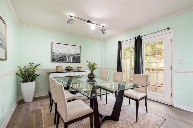 dining area with light wood-style flooring, baseboards, and crown molding