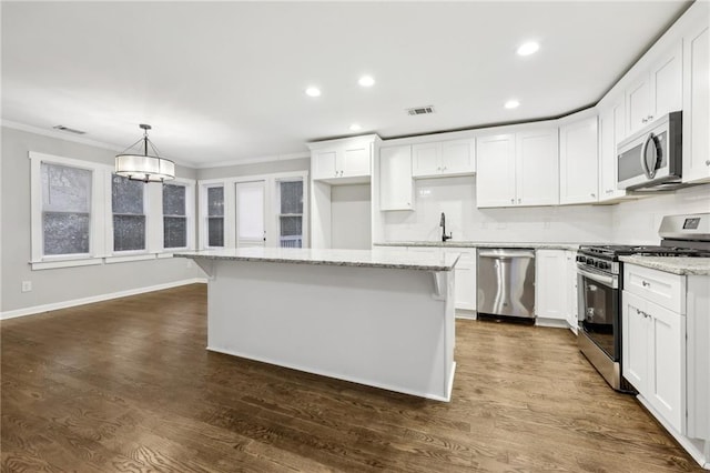 kitchen featuring stainless steel appliances, a kitchen island, white cabinetry, hanging light fixtures, and light stone countertops