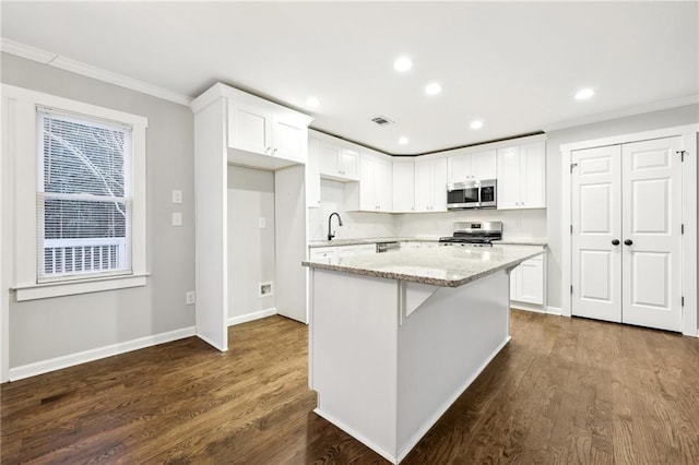 kitchen featuring appliances with stainless steel finishes, a sink, white cabinetry, and a center island