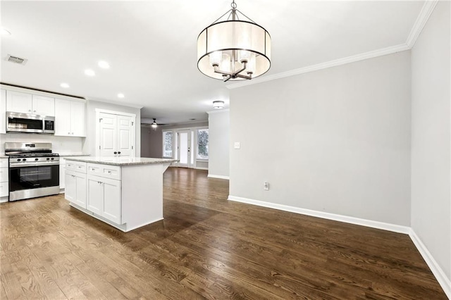 kitchen with hanging light fixtures, white cabinets, stainless steel appliances, and a center island