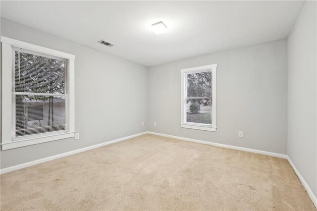 spare room with light carpet, baseboards, and visible vents