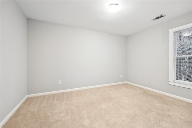 spare room featuring light carpet, baseboards, and visible vents